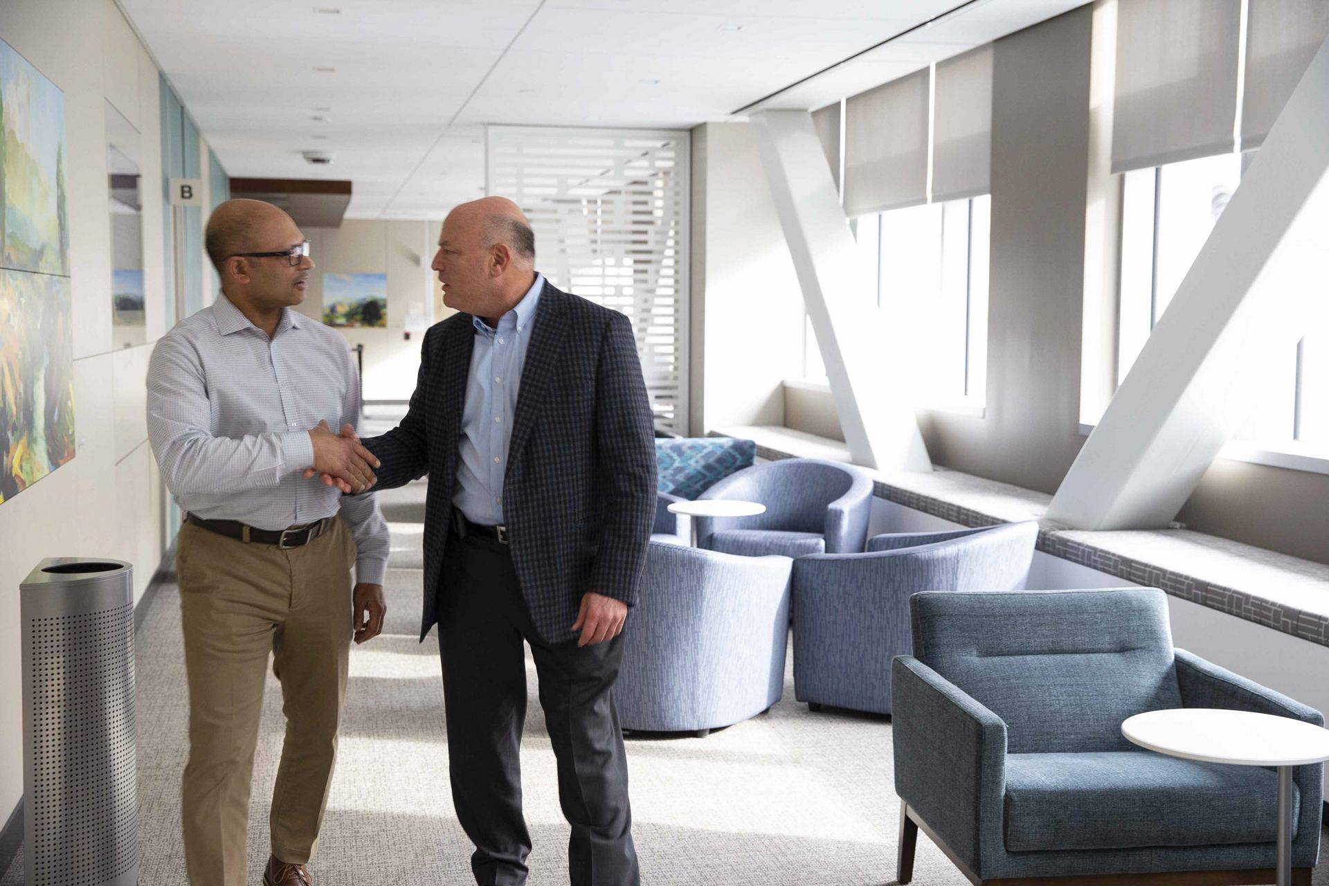 Two men shaking hands in a bright office lobby