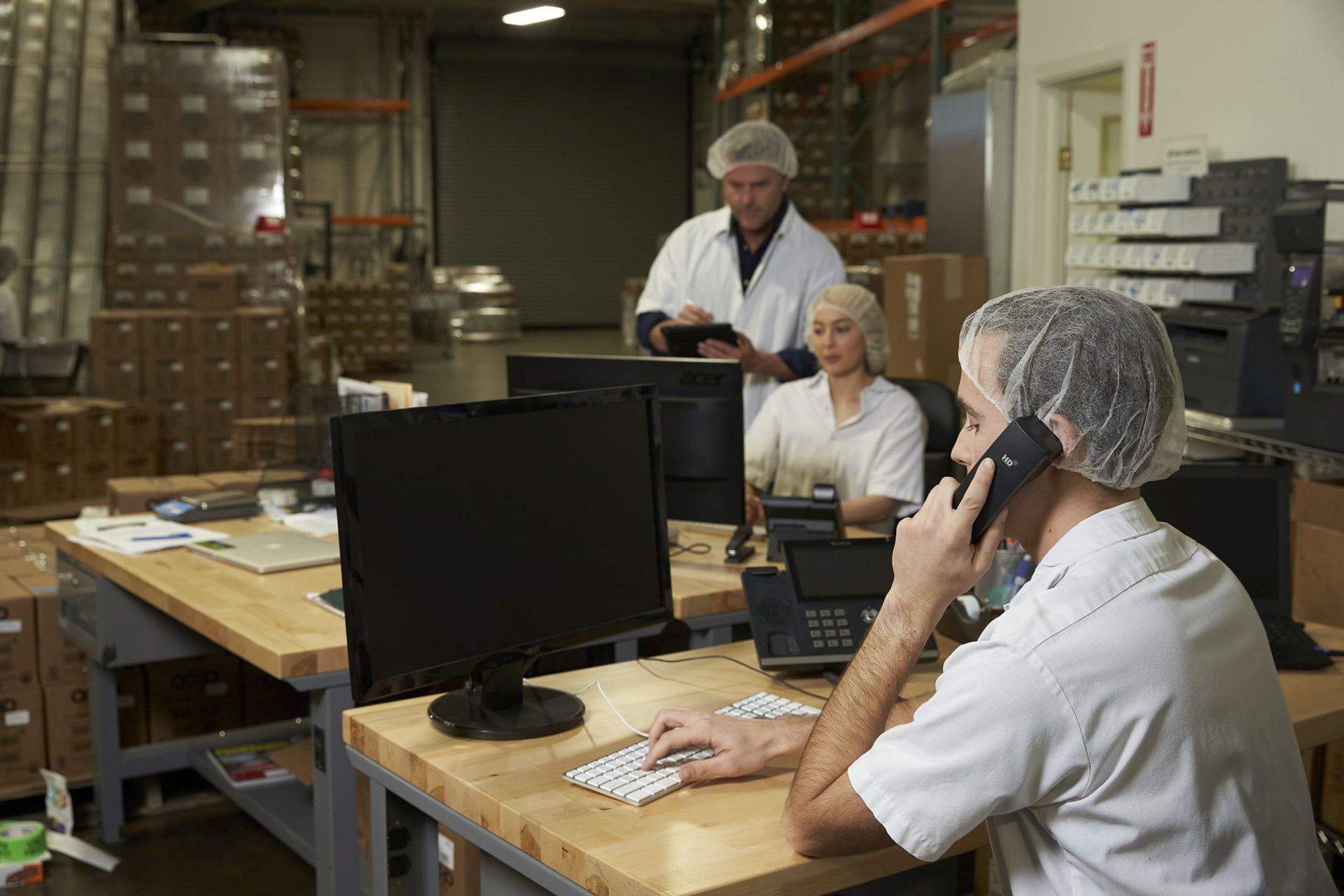 Office worker on a desk phone at a workstation on a production floor